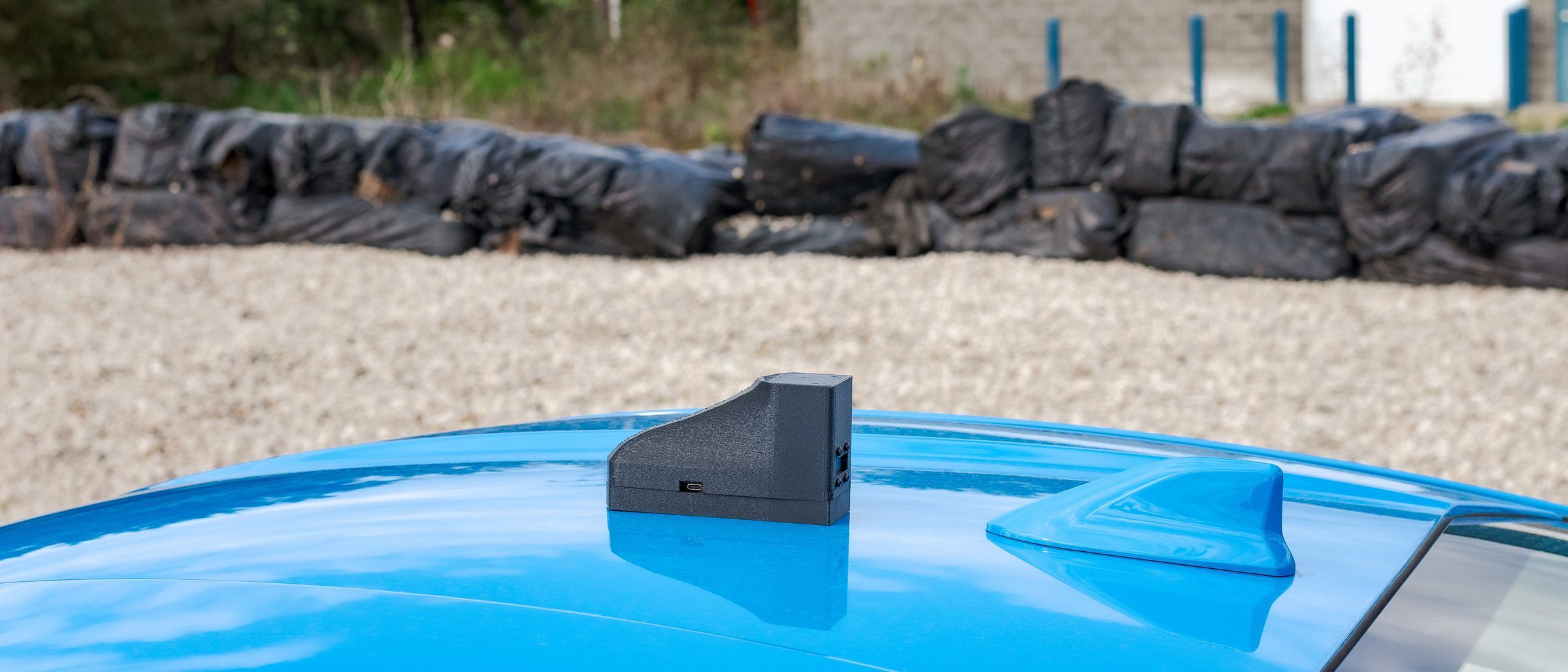 A small timing unit sitting on a car roof next to the factory antenna.